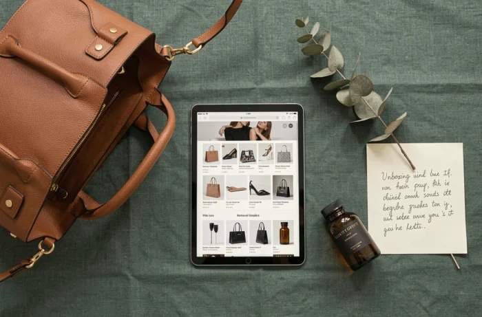 Flat lay élégant représentant l'expérience du shopping de luxe en ligne avec sac designer, tablette et accessoires haut de gamme